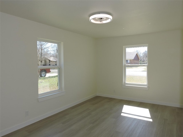 empty room featuring plenty of natural light, wood finished floors, and baseboards