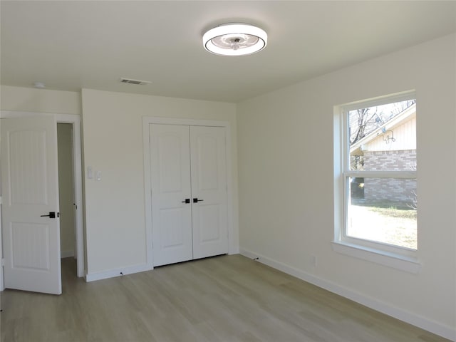 unfurnished bedroom with multiple windows, baseboards, and light wood finished floors