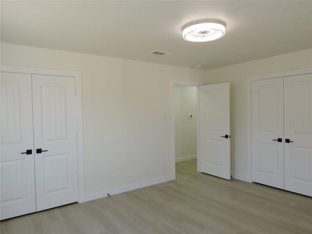 unfurnished bedroom featuring light wood finished floors, visible vents, a closet, and baseboards