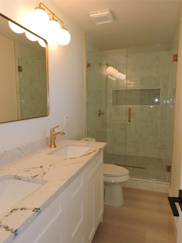 bathroom featuring wood finished floors, visible vents, a marble finish shower, a sink, and toilet