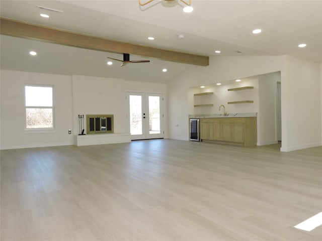 unfurnished living room featuring wine cooler, plenty of natural light, vaulted ceiling with beams, and a sink