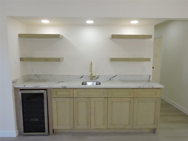 bar featuring baseboards, beverage cooler, recessed lighting, light wood-style flooring, and a sink