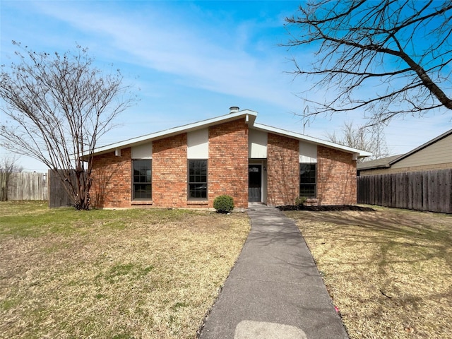 mid-century inspired home with brick siding, a front yard, and fence