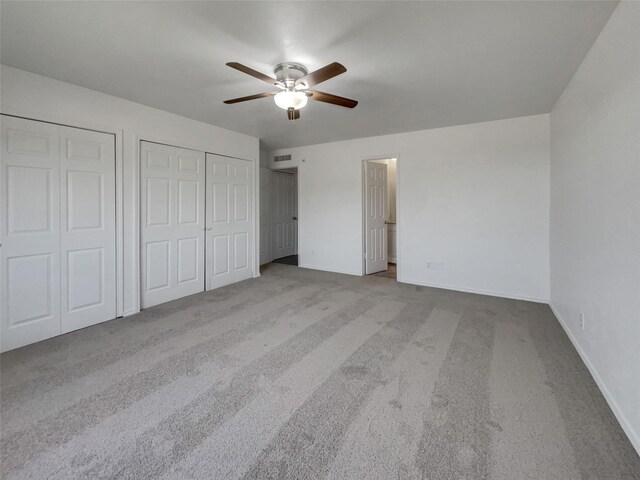 carpeted spare room featuring baseboards and a ceiling fan