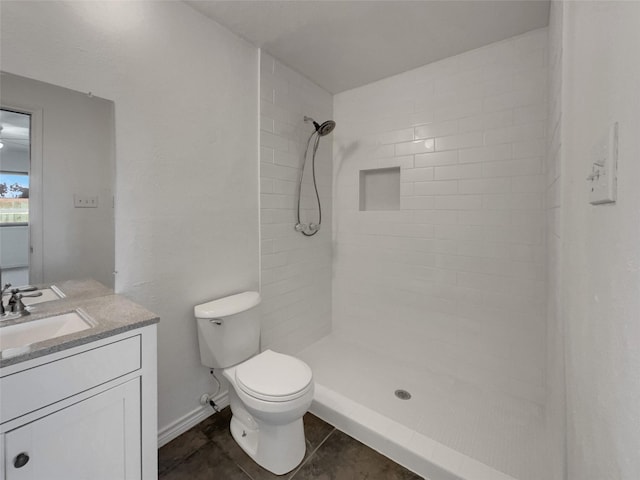 full bath featuring vanity, baseboards, tiled shower, tile patterned floors, and toilet