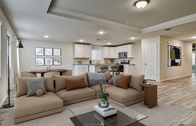 living area featuring visible vents, recessed lighting, crown molding, light wood finished floors, and a raised ceiling