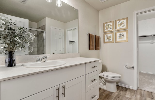 bathroom with visible vents, toilet, a stall shower, wood finished floors, and vanity