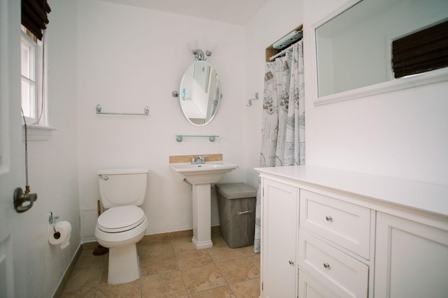 bathroom with baseboards, toilet, and tile patterned flooring