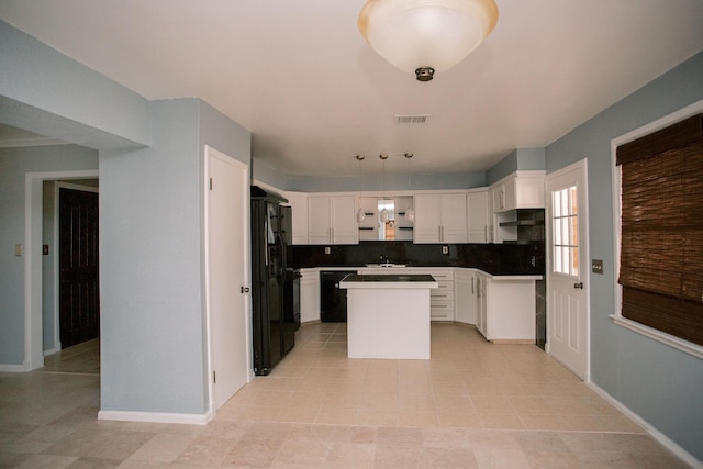 kitchen with visible vents, a center island, decorative backsplash, black fridge, and white cabinetry