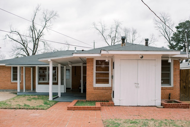 back of house with brick siding and covered porch