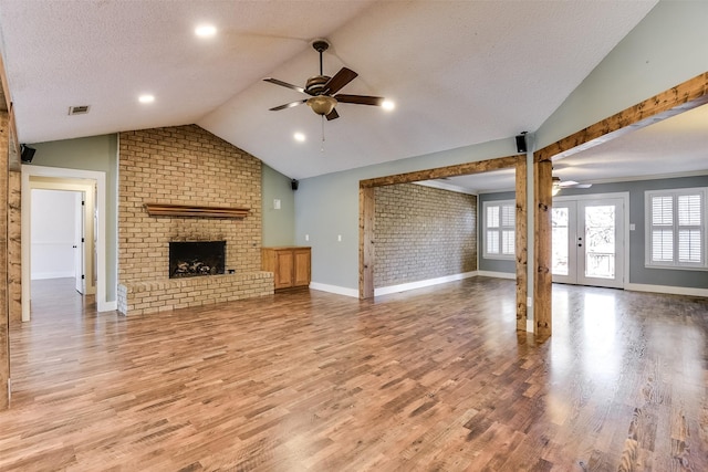 unfurnished living room featuring visible vents, ceiling fan, vaulted ceiling, a fireplace, and a textured ceiling