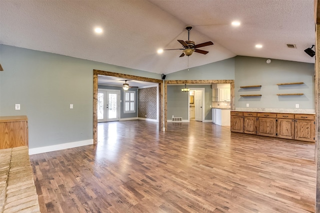 unfurnished living room with light wood finished floors, visible vents, ceiling fan, french doors, and a textured ceiling