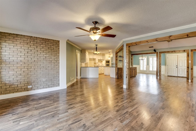 unfurnished living room with a textured ceiling, wood finished floors, ornamental molding, and ceiling fan with notable chandelier