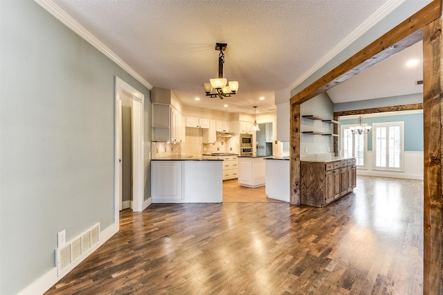 kitchen with dark countertops, visible vents, an inviting chandelier, wood finished floors, and a textured ceiling