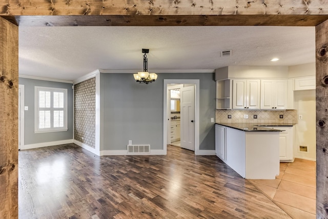 kitchen featuring dark countertops, visible vents, a textured ceiling, and wood finished floors