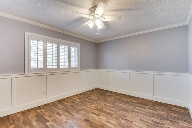 spare room with a ceiling fan, wood finished floors, a wainscoted wall, ornamental molding, and a textured ceiling