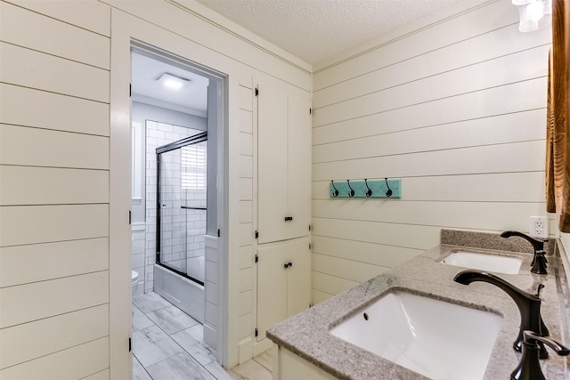 full bathroom with a sink, a textured ceiling, marble finish floor, and combined bath / shower with glass door