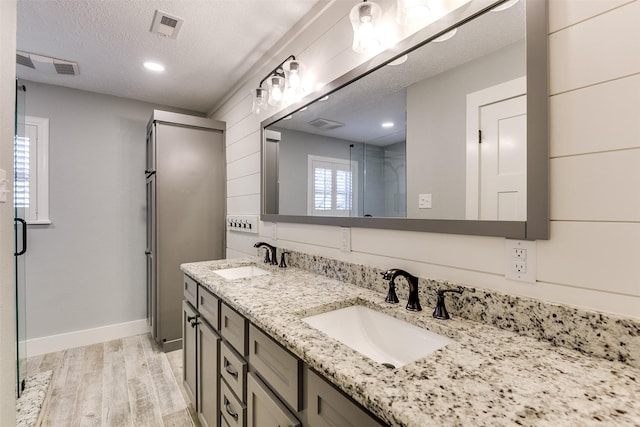 bathroom featuring visible vents, a textured ceiling, wood finished floors, and a sink