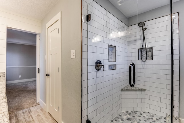 bathroom with baseboards, wood finished floors, a stall shower, and a textured ceiling