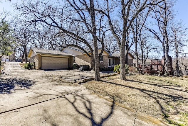 view of front of property featuring a garage, brick siding, driveway, and a wooden deck