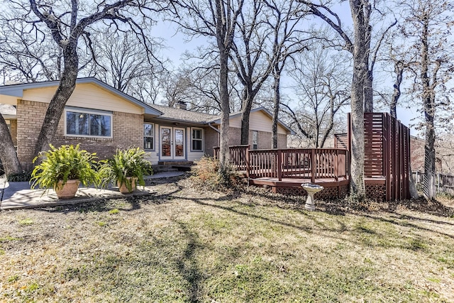 back of house with a wooden deck, a yard, a chimney, french doors, and brick siding