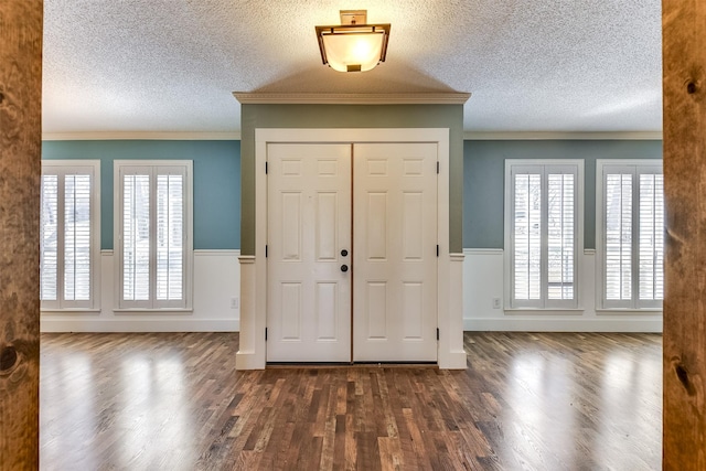 foyer featuring a textured ceiling, dark wood finished floors, and wainscoting