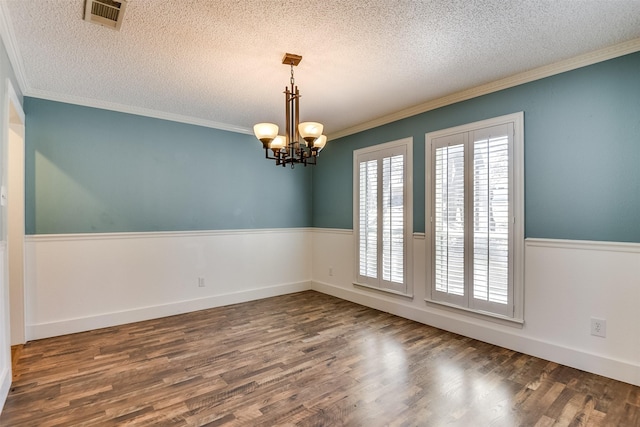 empty room featuring visible vents, ornamental molding, and wood finished floors