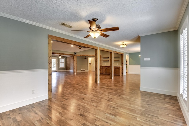 unfurnished room with visible vents, light wood-style flooring, crown molding, and ceiling fan