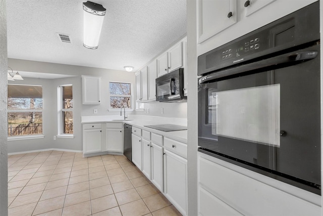 kitchen featuring visible vents, light tile patterned floors, white cabinets, black appliances, and a sink