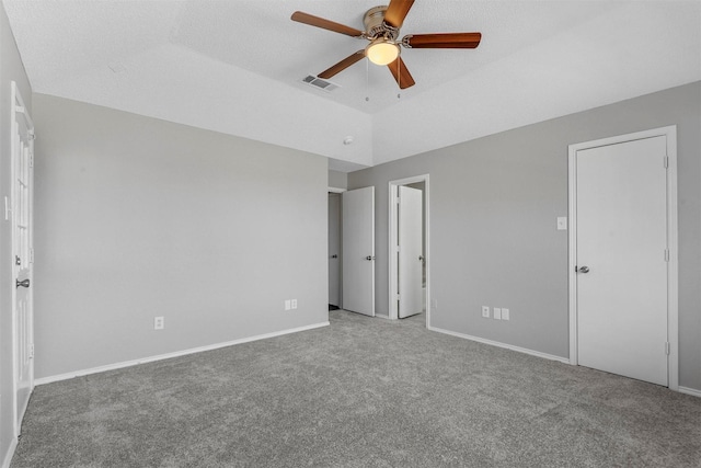 unfurnished bedroom featuring visible vents, baseboards, carpet, vaulted ceiling, and a ceiling fan