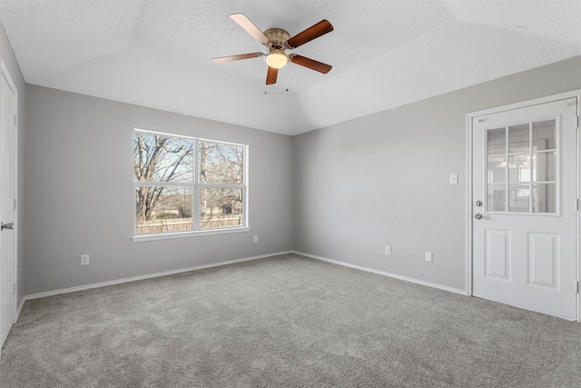 carpeted empty room with a textured ceiling, baseboards, and a ceiling fan