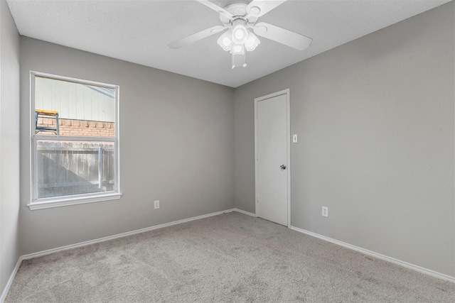 carpeted empty room featuring baseboards, a textured ceiling, and a ceiling fan