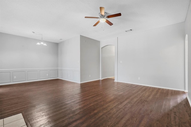 spare room with ceiling fan with notable chandelier, wood finished floors, visible vents, and arched walkways