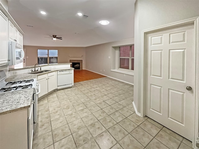 kitchen with a ceiling fan, a sink, white appliances, a peninsula, and white cabinets