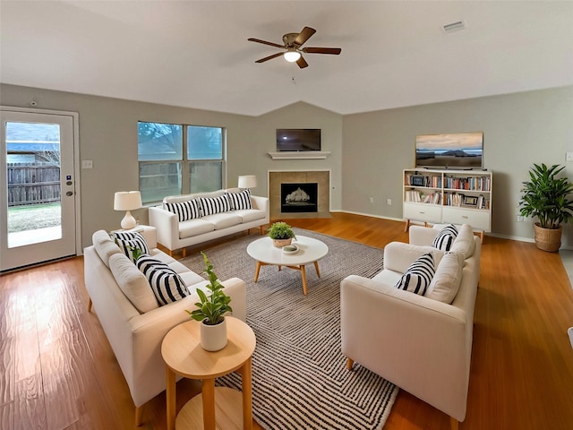 living area with visible vents, a fireplace, lofted ceiling, and wood finished floors