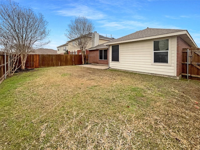 rear view of property featuring a patio area, a lawn, a fenced backyard, and roof with shingles