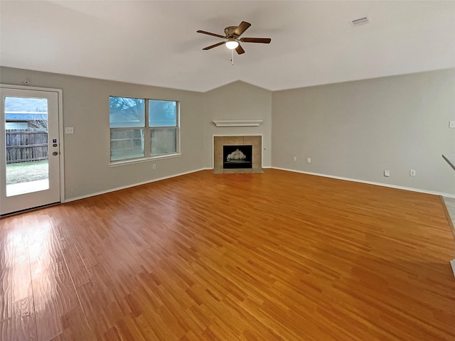 unfurnished living room with visible vents, light wood-style flooring, a fireplace, ceiling fan, and vaulted ceiling