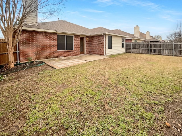 back of property with a patio, a yard, a fenced backyard, and brick siding