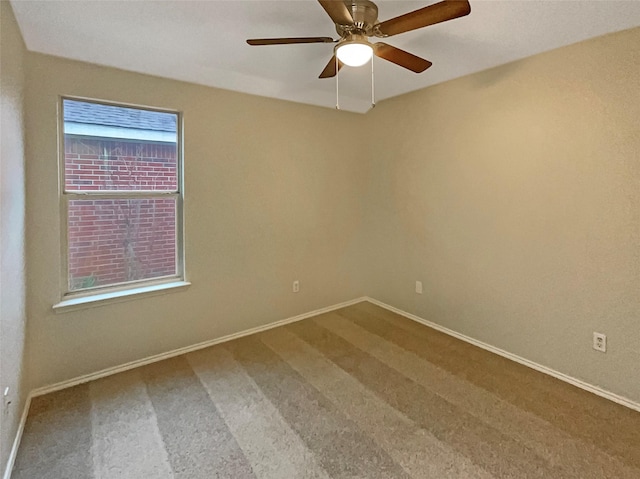 carpeted spare room with baseboards and a ceiling fan