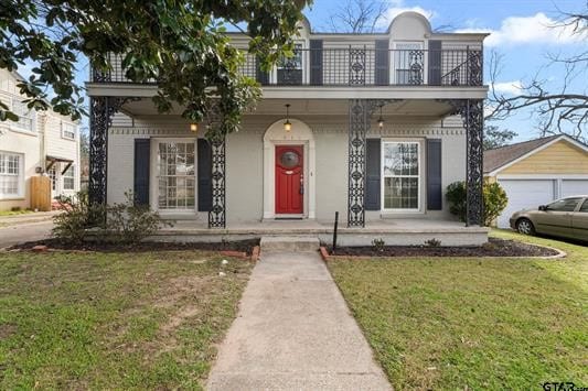 view of front facade featuring covered porch, a front lawn, and a balcony