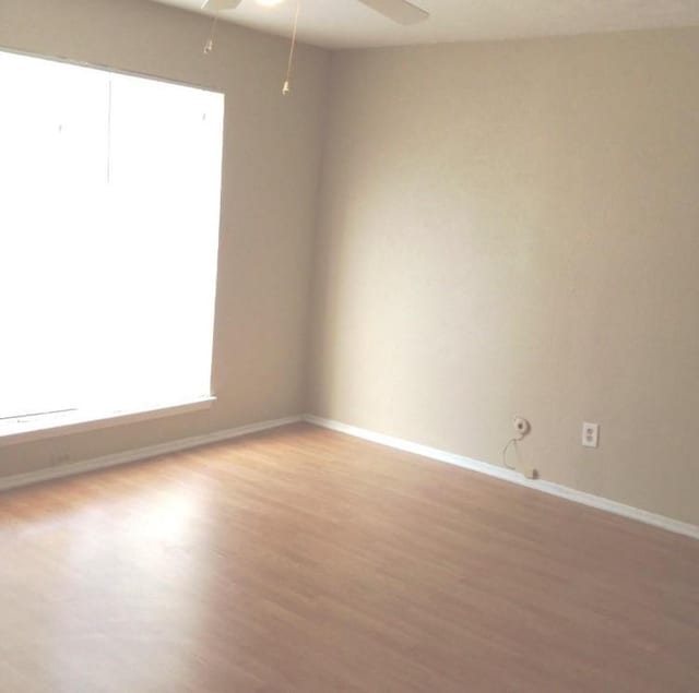 unfurnished room with baseboards, ceiling fan, and light wood finished floors