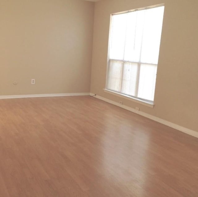 spare room with baseboards and light wood-style flooring