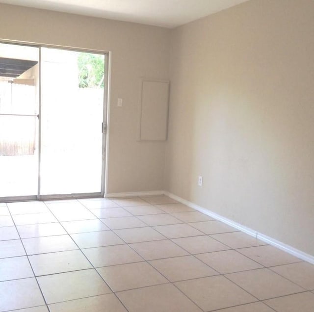 empty room with light tile patterned floors and baseboards