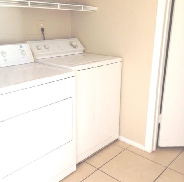 laundry room featuring laundry area, light tile patterned floors, separate washer and dryer, and baseboards