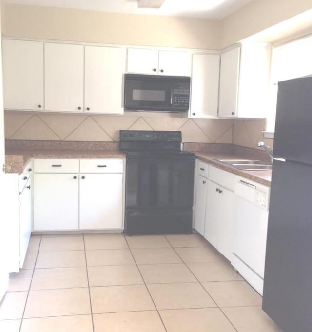 kitchen with light tile patterned floors, white cabinets, black appliances, and a sink