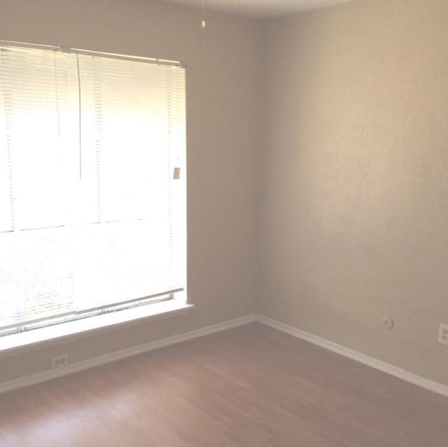 empty room with baseboards and wood finished floors