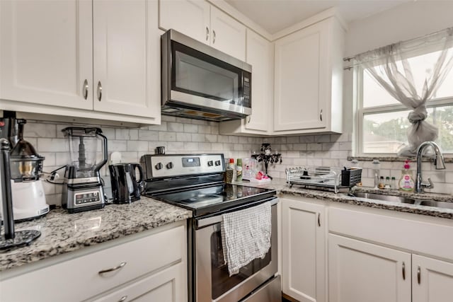 kitchen featuring white cabinetry, decorative backsplash, appliances with stainless steel finishes, and a sink