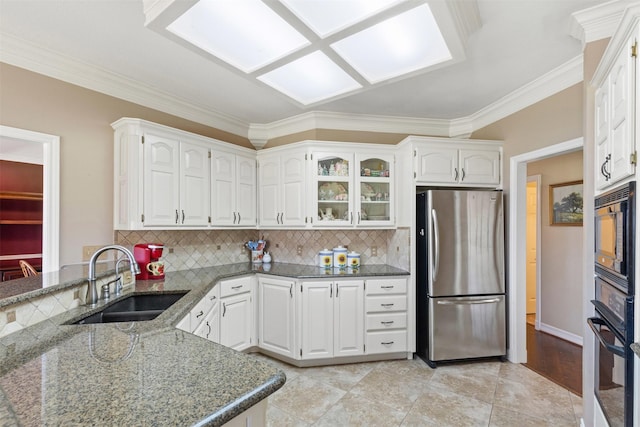 kitchen with oven, a sink, freestanding refrigerator, dark stone counters, and built in microwave