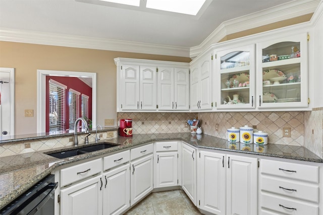 kitchen with glass insert cabinets, dishwasher, dark stone countertops, white cabinets, and a sink