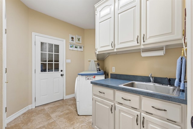 washroom with cabinet space, baseboards, and a sink